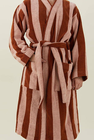 Person wearing blush and terracotta striped bathrobe