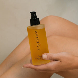 Hand holding a bottle of 'Daydream' product with a neutral background