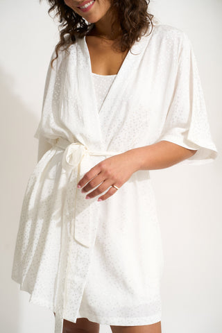 Woman wearing short white robe with matching scrunchie
