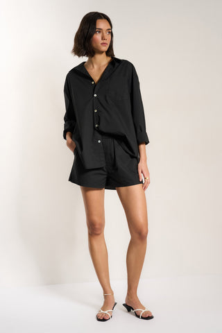 Woman wearing black cotton button up shirt with matching shorts