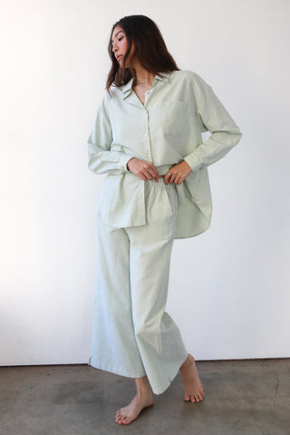 Woman wearing green and white pinstripe boxer pants and matching button-up shirt
