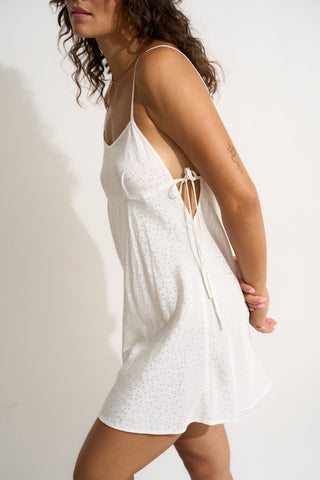 Woman wearing a short white nightgown with adjustable side ties
