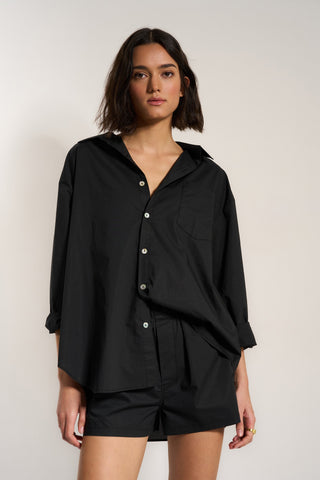 Woman wearing black cotton button up shirt with matching shorts
