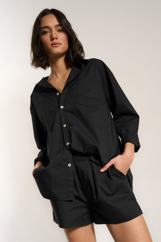 Woman wearing black cotton button up shirt with matching shorts