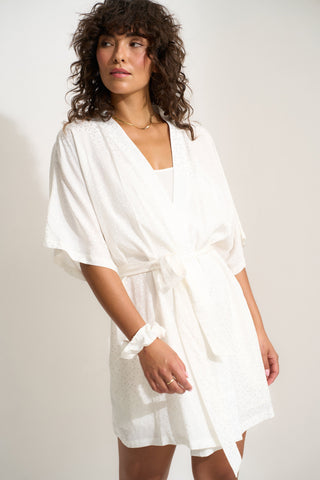 Woman wearing short white robe with matching scrunchie