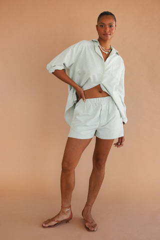 Woman wearing green and white pinstripe boxer shorts with matching top