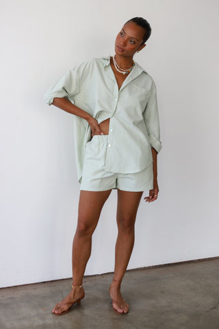 Woman wearing green and white pinstripe boxer shorts with matching button-up shirt