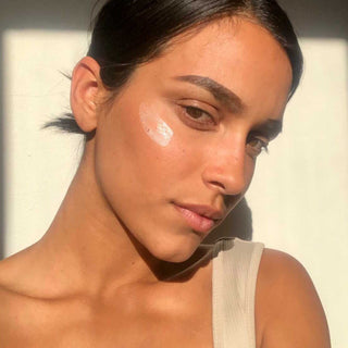 Woman with rosewater cream on her face against a neutral background