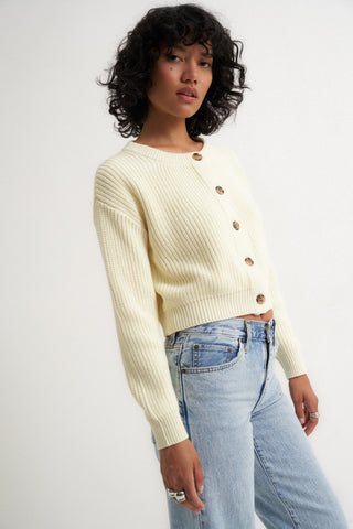 Woman wearing a cream ribbed cardigan sweater with front buttons