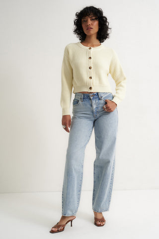 Woman wearing a cream ribbed cardigan sweater with front buttons