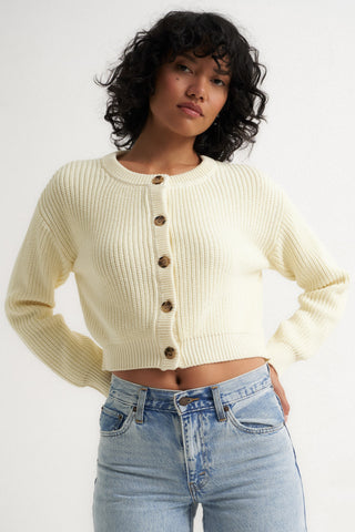 Woman wearing a cream ribbed cardigan sweater with front buttons