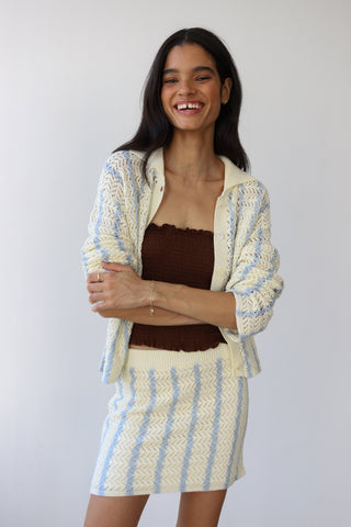 Woman wearing a cream and light blue crochet button down sweater