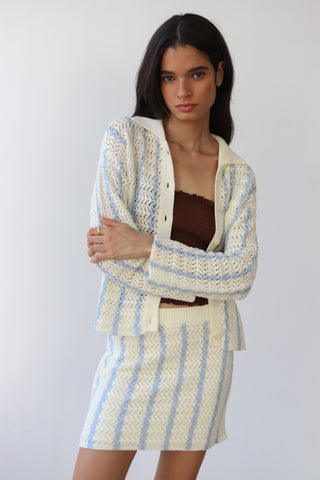 Woman wearing a cream and light blue crochet button down sweater