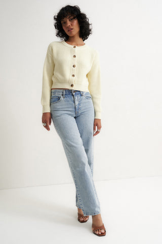 Woman wearing a cream ribbed cardigan sweater with front buttons