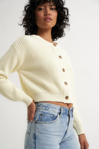 Woman wearing a cream ribbed cardigan sweater with front buttons