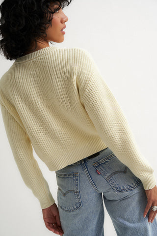 Woman wearing a cream ribbed cardigan sweater with front buttons
