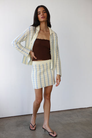 Woman wearing a cream and light blue crochet button down sweater