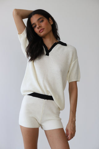 Woman wearing creme knit shorts with black detail elastic waistband and matching top
