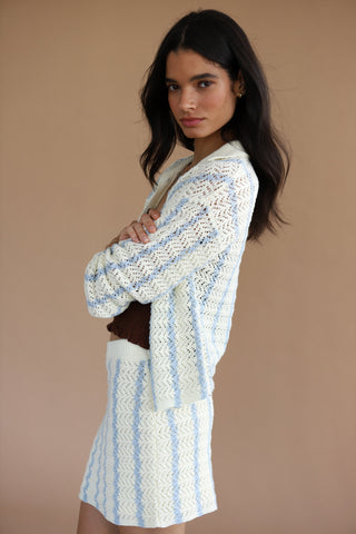 Woman wearing a cream and light blue crochet button down sweater