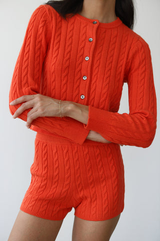 Woman wearing bright red casual knit shorts and matching cardigan top
