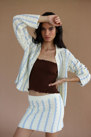 Woman wearing a cream and light blue crochet button down sweater