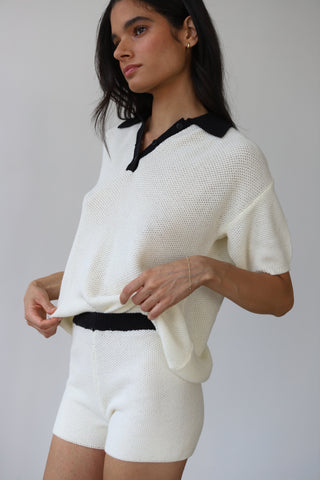 Woman wearing creme knit shorts with black detail elastic waistband and matching top