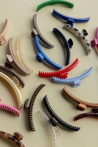 Assorted colorful hair claw clips on a beige background