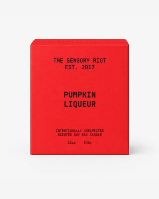 A red rectangular box for a scented soy wax candle with black text reading 'THE SENSORY RIOT EST. 2017', 'PUMPKIN LIQUEUR', and 'INTENTIONALLY UNEXPECTED SCENTED SOY WAX CANDLE 12oz 340g' on a light gray background.