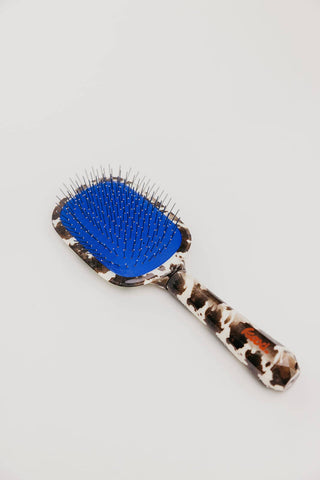 Cow print hairbrush with blue accent and metal bristles