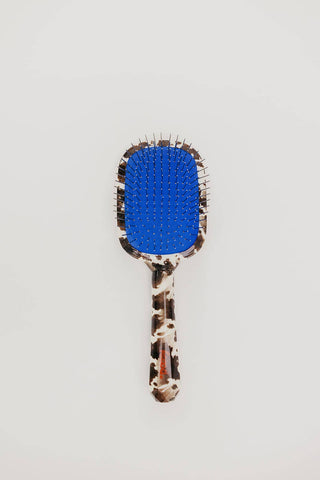 Cow print hairbrush with blue accent and metal bristles