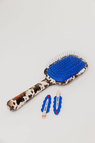 Cow print hairbrush with blue accent, matching blue hair clips