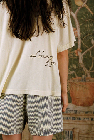 Woman wearing yellow and green striped pajama shorts with sleep t-shirt