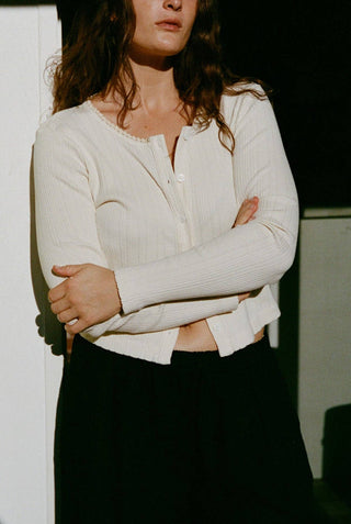 Woman wearing LA Relaxed pointelle cardigan with pearl buttons shown in natural color