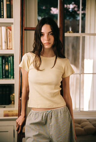 Woman wearing yellow and green striped pajama shorts with cozy yellow shirt