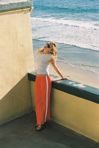 Woman wearing red pointelle cotton track pants with white side stripe detail