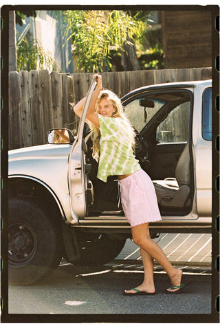 Woman wearing pink cotton poplin shorts with green and white tie-dyed shirt