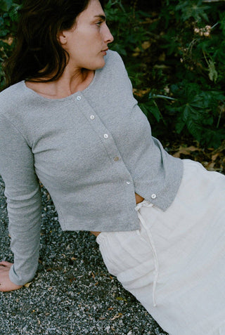 Woman wearing heather gray cotton ribbed cardigan with cropped fit and pearl front buttons