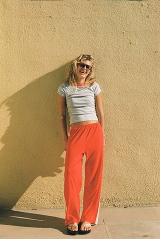 Woman wearing red pointelle cotton track pants with white side stripe detail