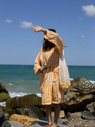 Girl by beach in lightweight yellow and white stripe cotton linen robe