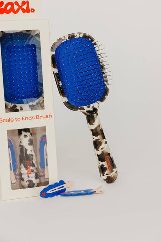 Cow print hairbrush with blue accent and metal bristles and matching clips