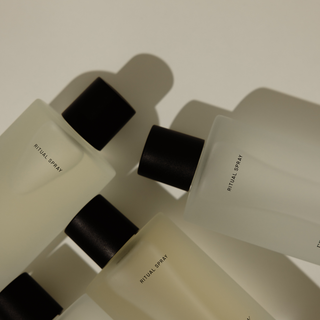Multiple bottles of 'Ritual Spray' arranged on a light surface with a neutral background.
