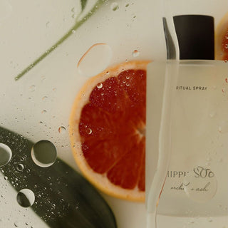 Spray bottle labeled 'Ritual Spray, Hippy Soul' next to a sliced grapefruit on a wet surface