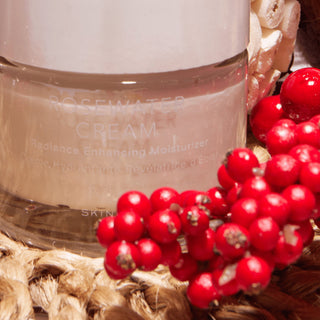 Rosewater cream jar with red berries on a textured surface