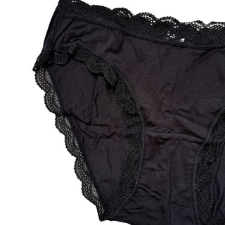 Close up view of black lace-trimmed underwear on a white background