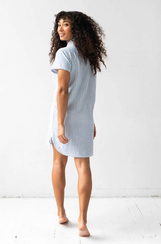 Woman wearing short sleeve button down sleep shirt in blue and white stripes with pink trim.