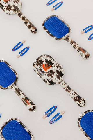 Cow print hairbrush with blue bristle head and matching blue clips